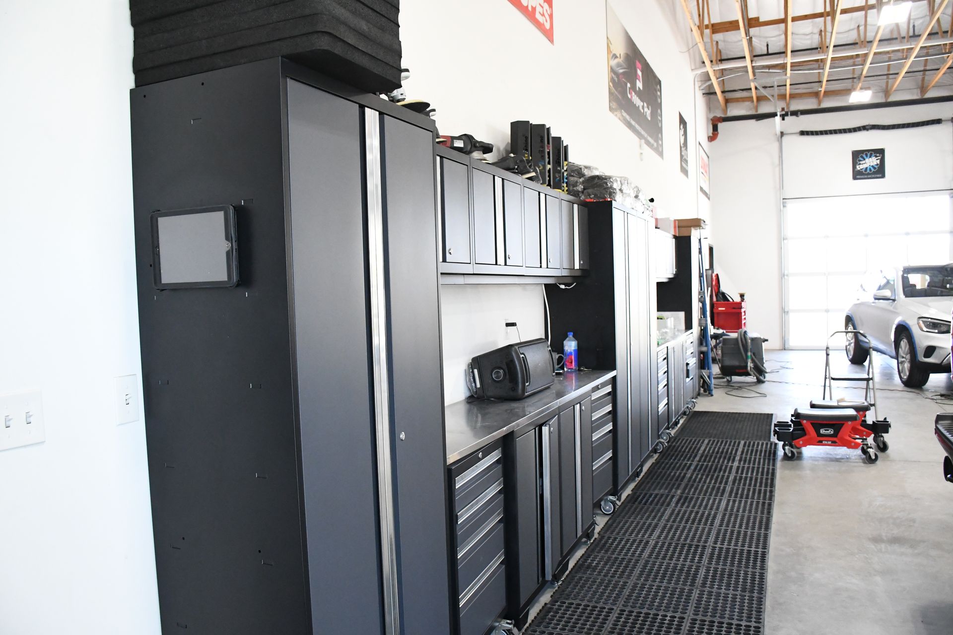 A car is parked in a garage with black cabinets