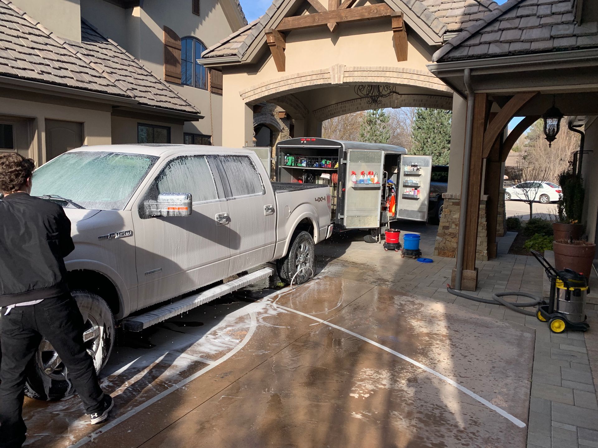 A man is washing a truck in front of a house.