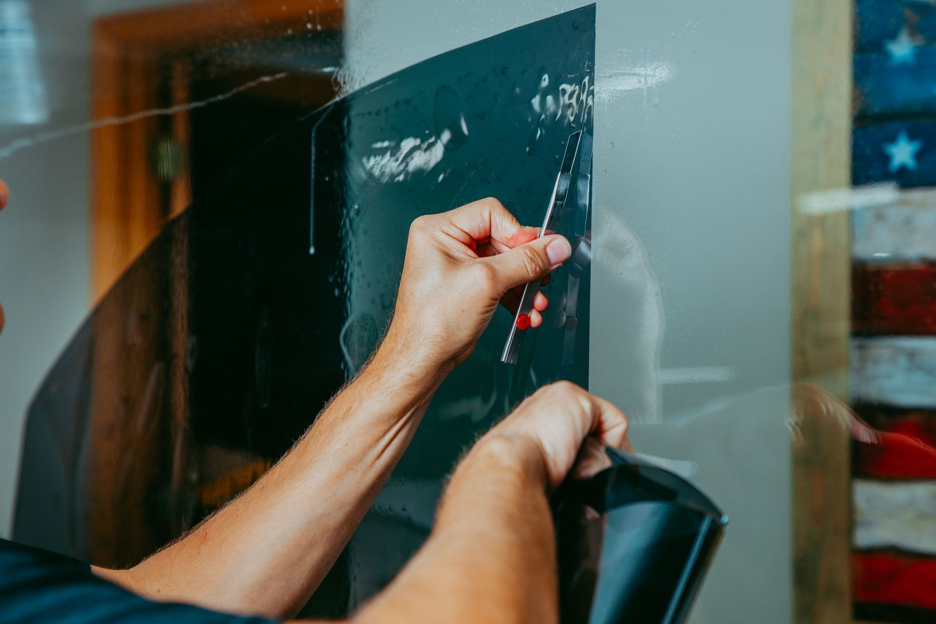 A man is applying tinted glass to a window.