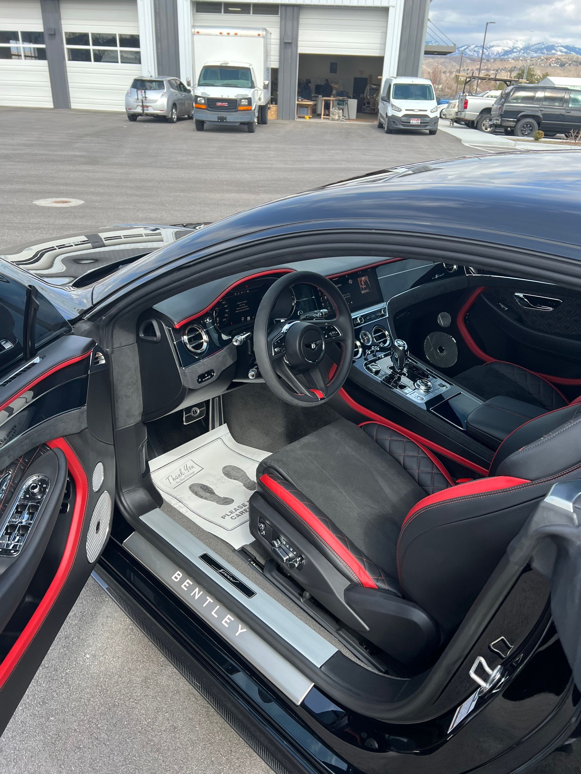 The interior of a black bentley with red seats is shown with the door open.