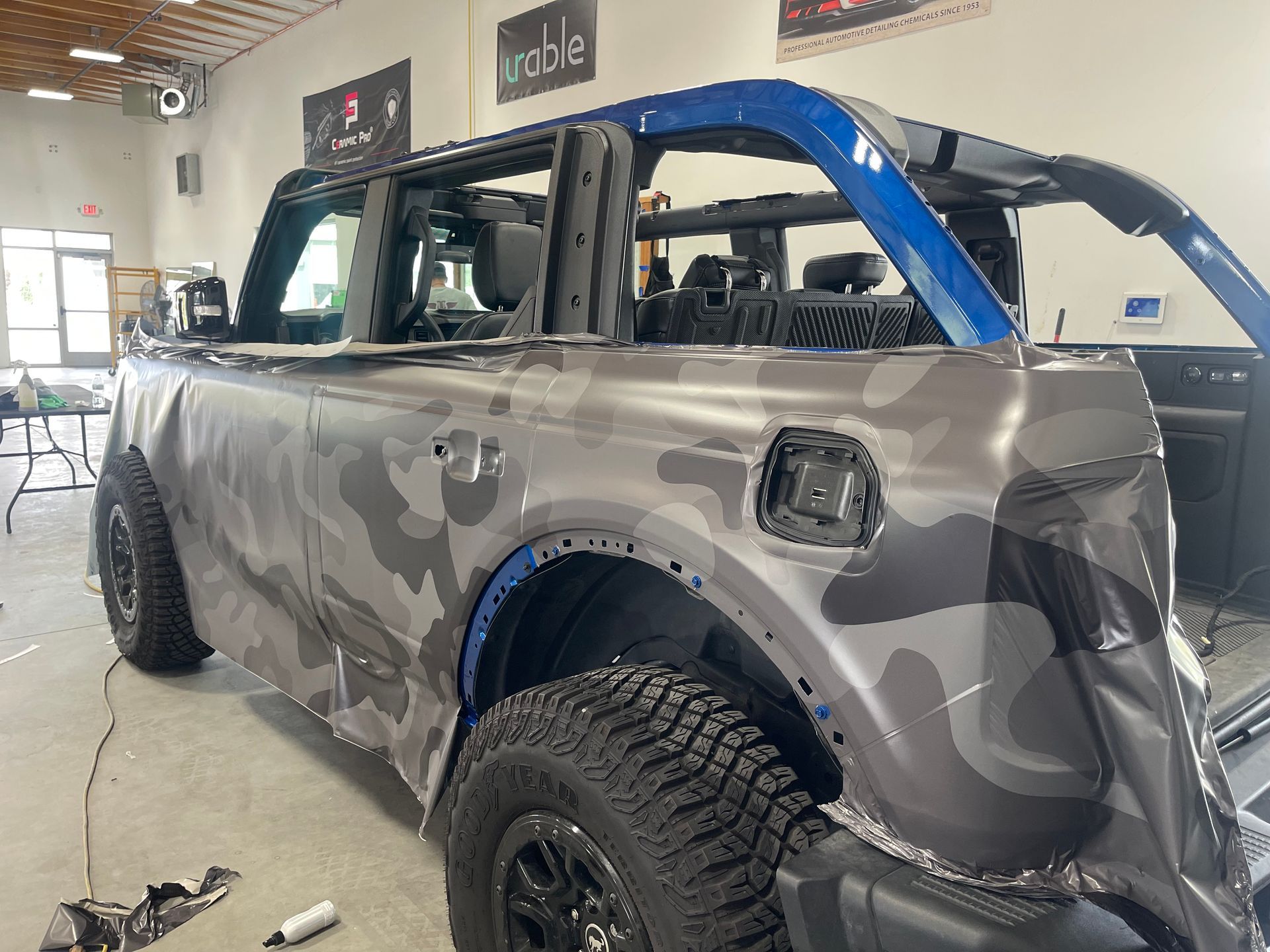 A truck is wrapped in a camouflage wrap in a garage.