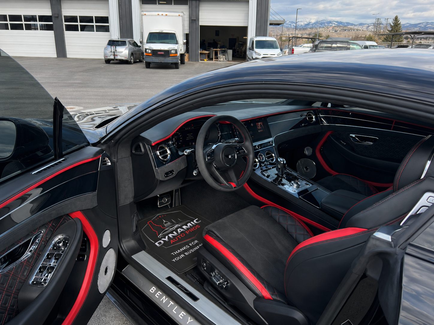 The interior of a Bentley with black and red  seats is shown with the door open.