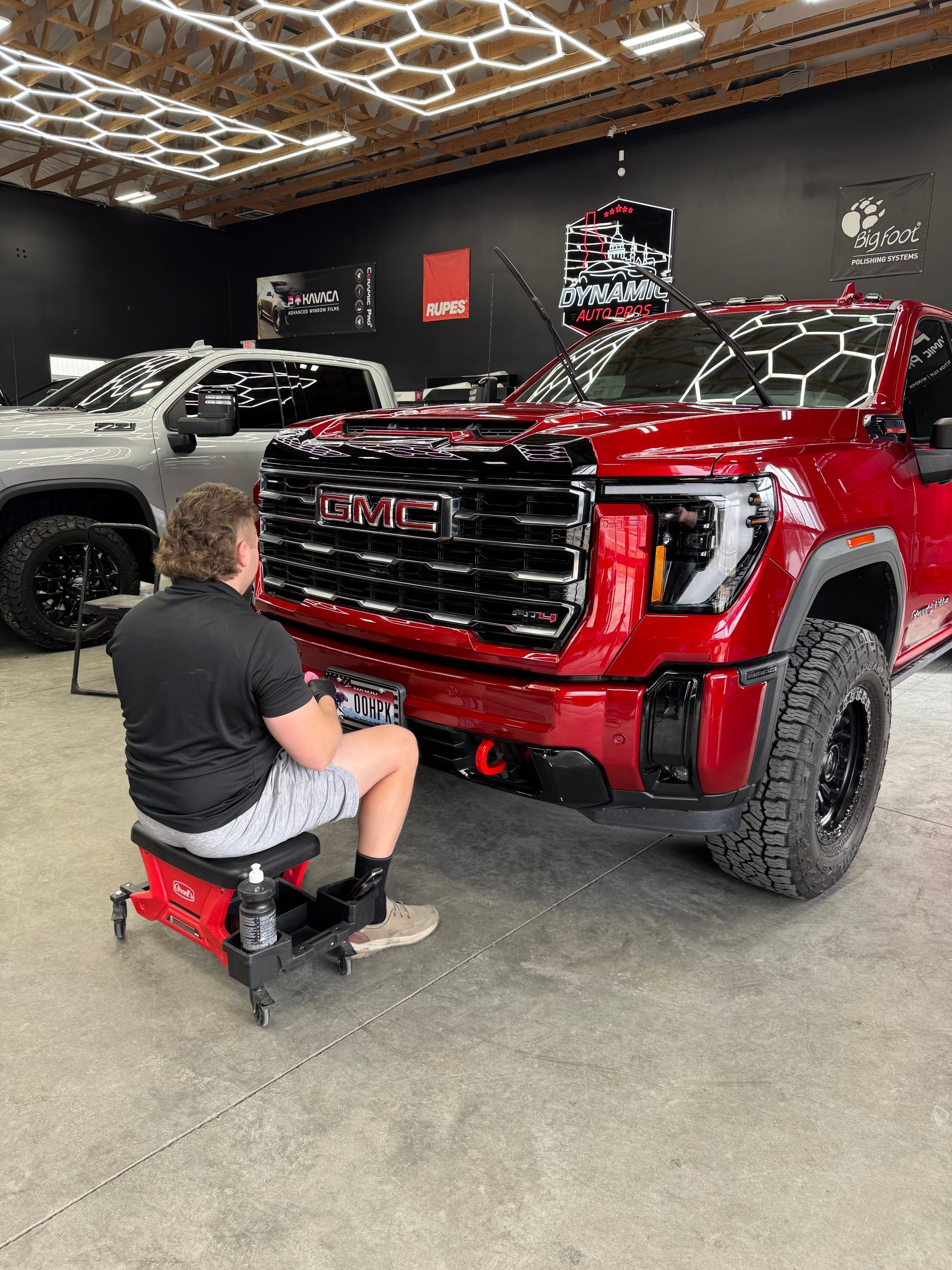 A man is polishing the fender of a red truck.
