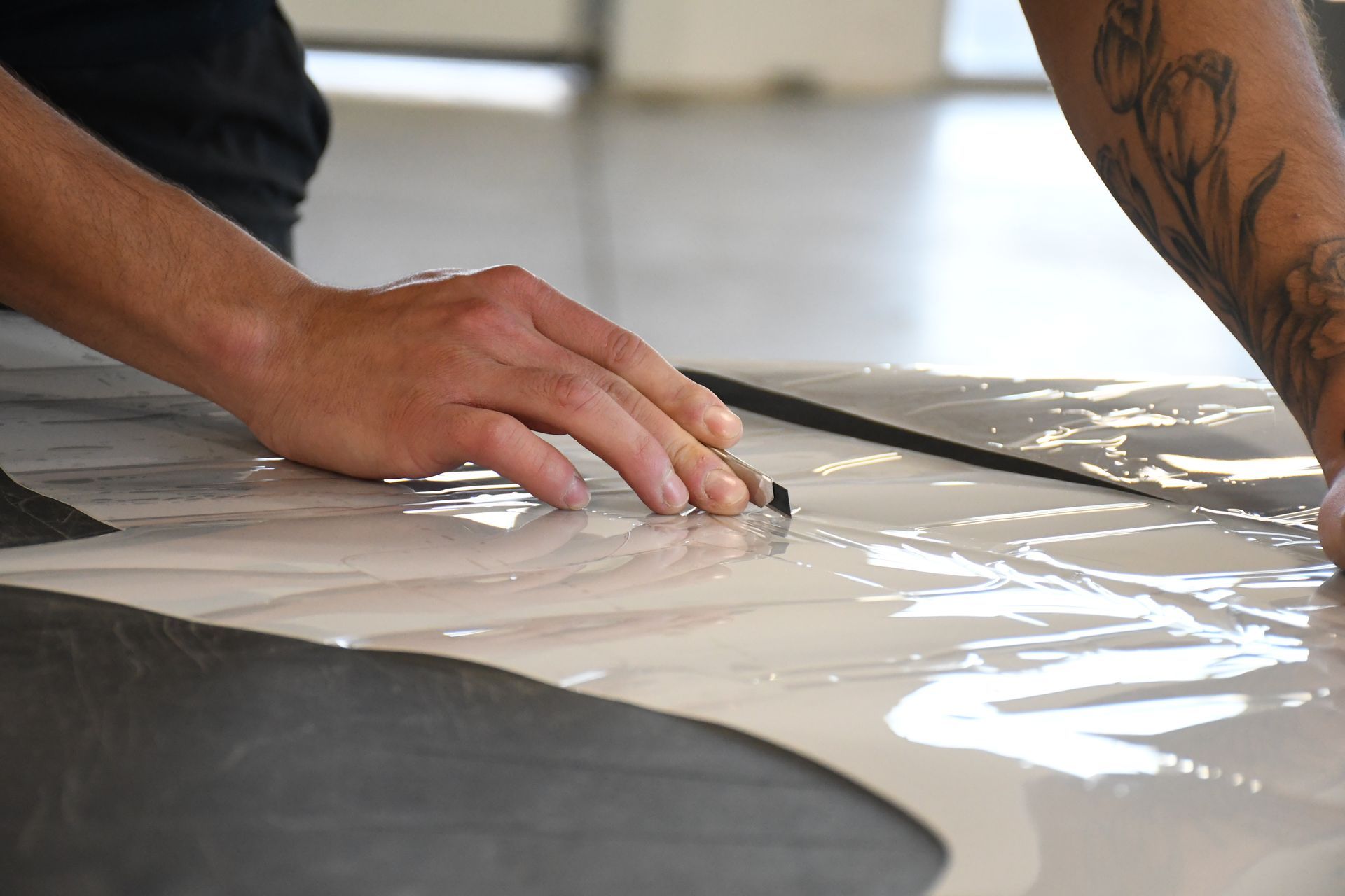 A man is cutting a piece of plastic on the floor.