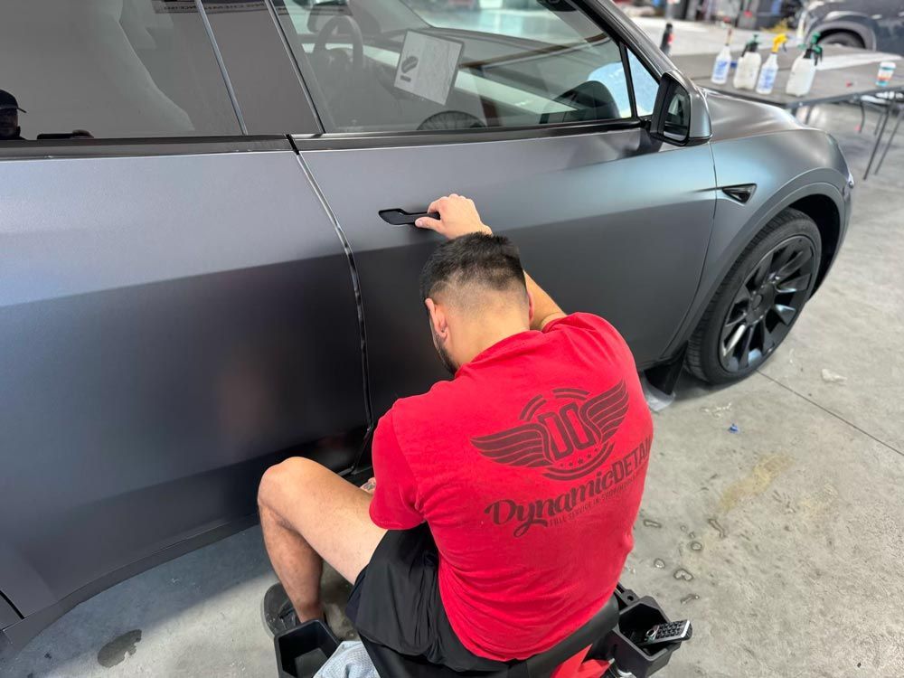 A man in a red shirt is sitting on a motorcycle next to a car.