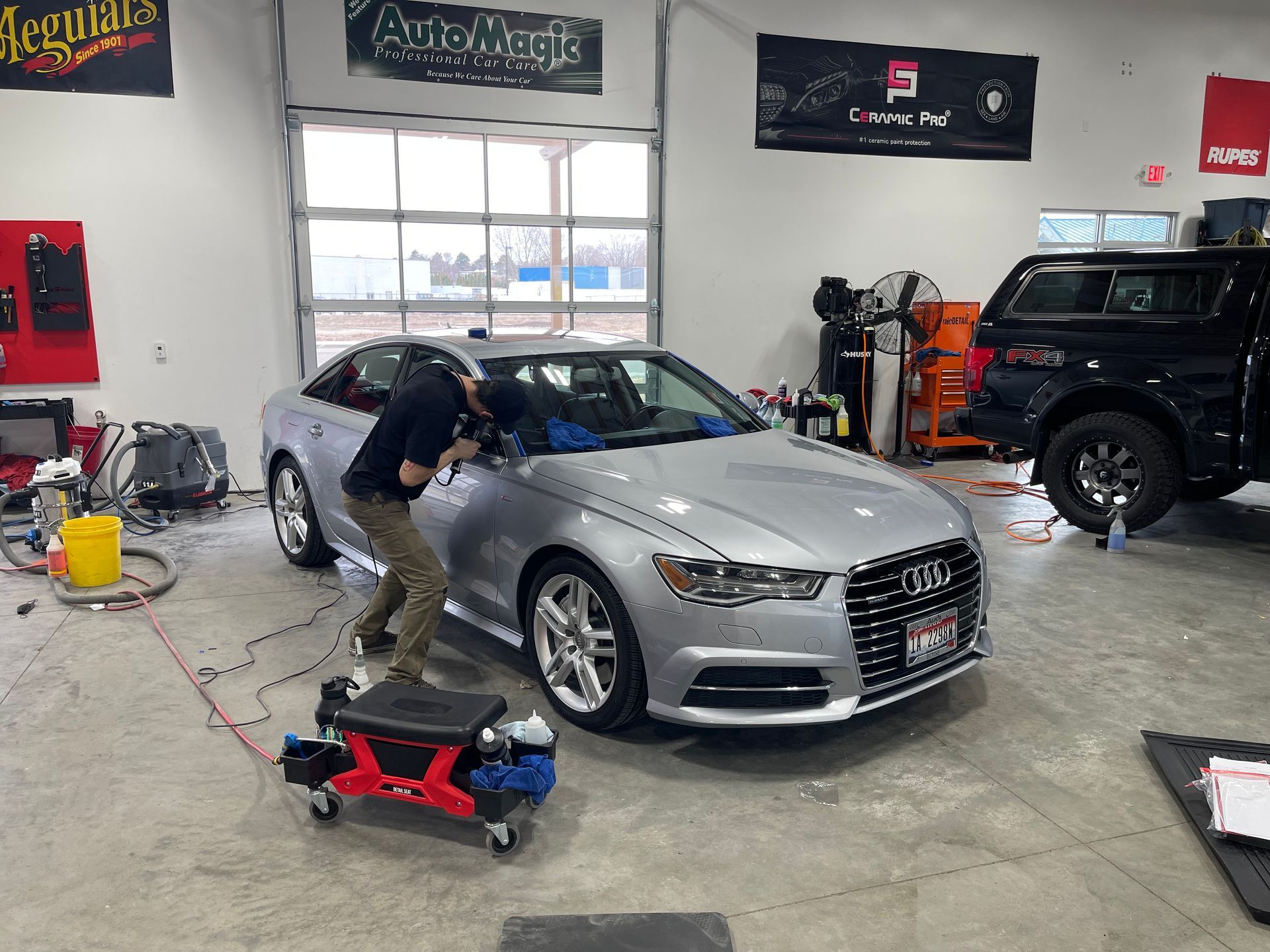 A woman is cleaning the wheel of a white car.