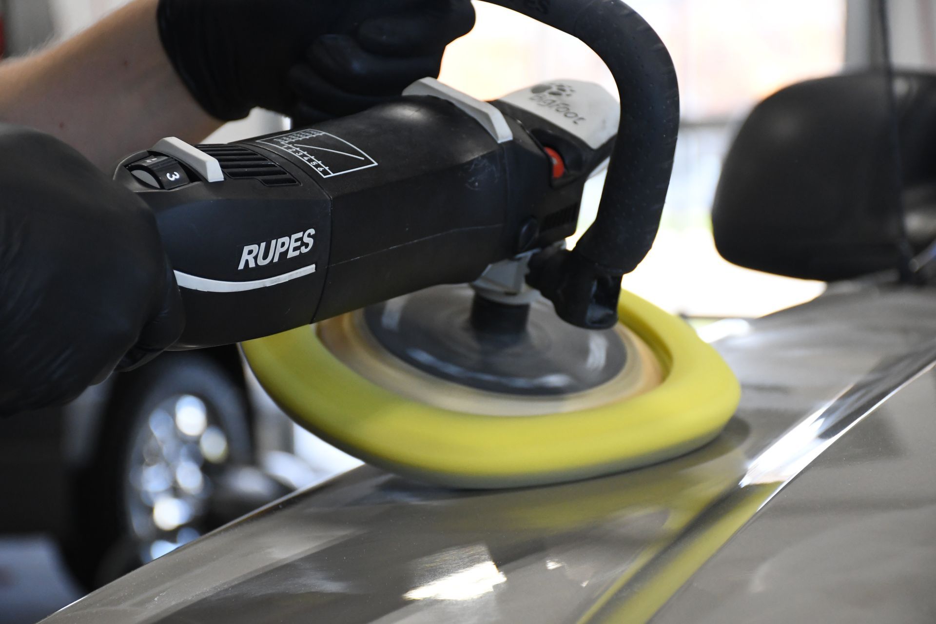 A person is polishing a car with a machine.