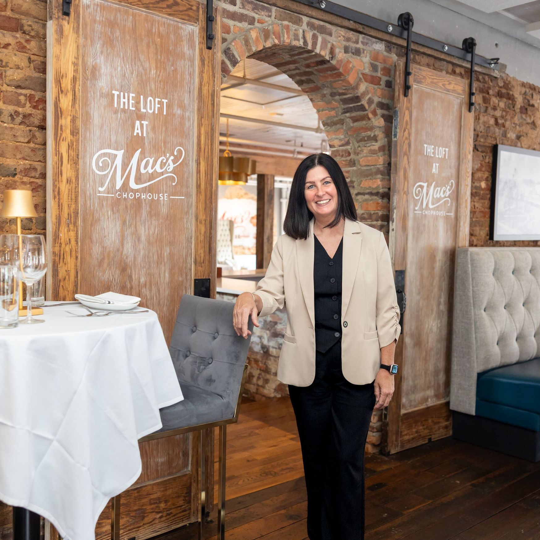 A woman is standing in front of a sign that says the loft at mac 's