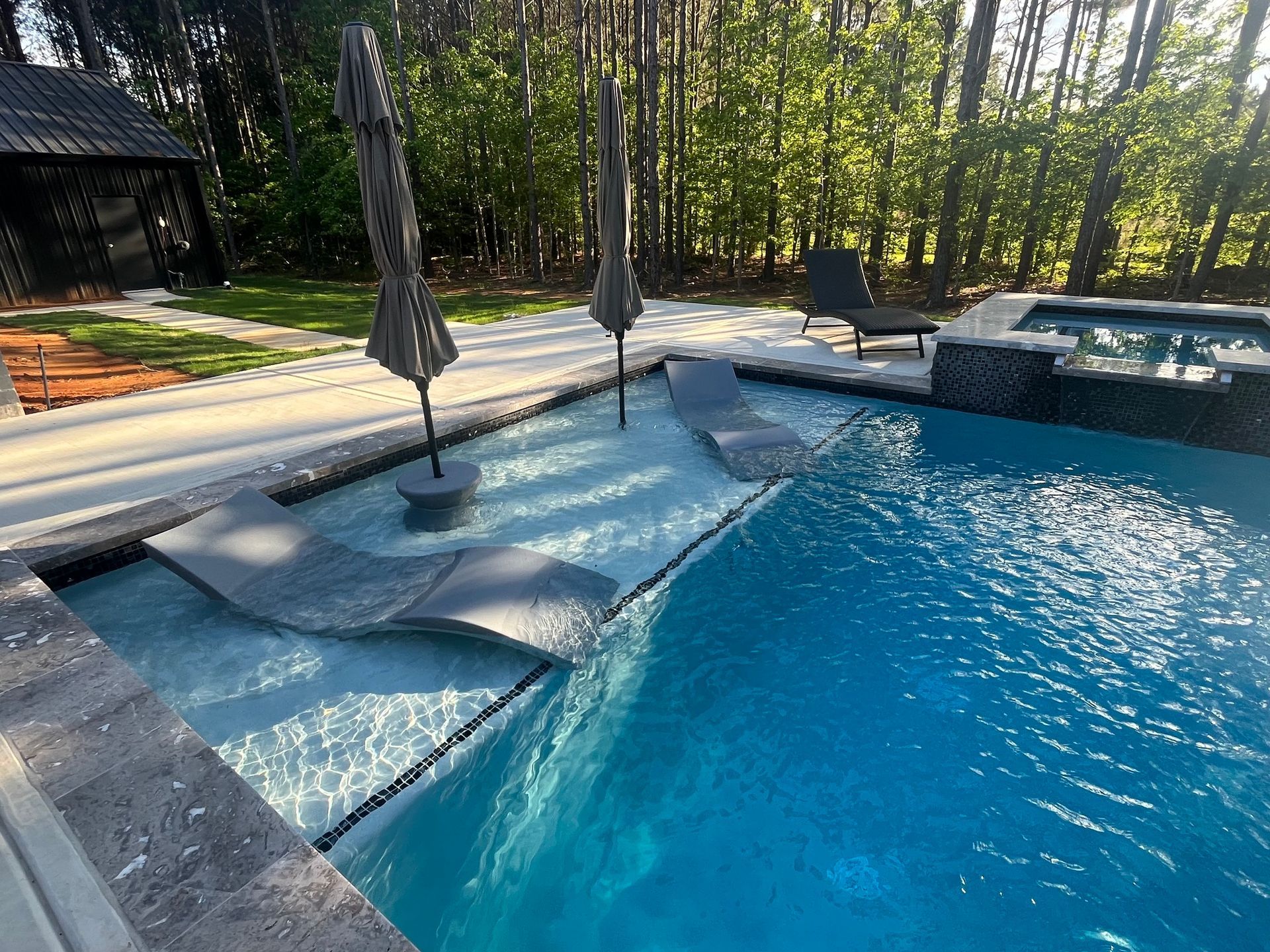 A large swimming pool with umbrellas and chairs in it