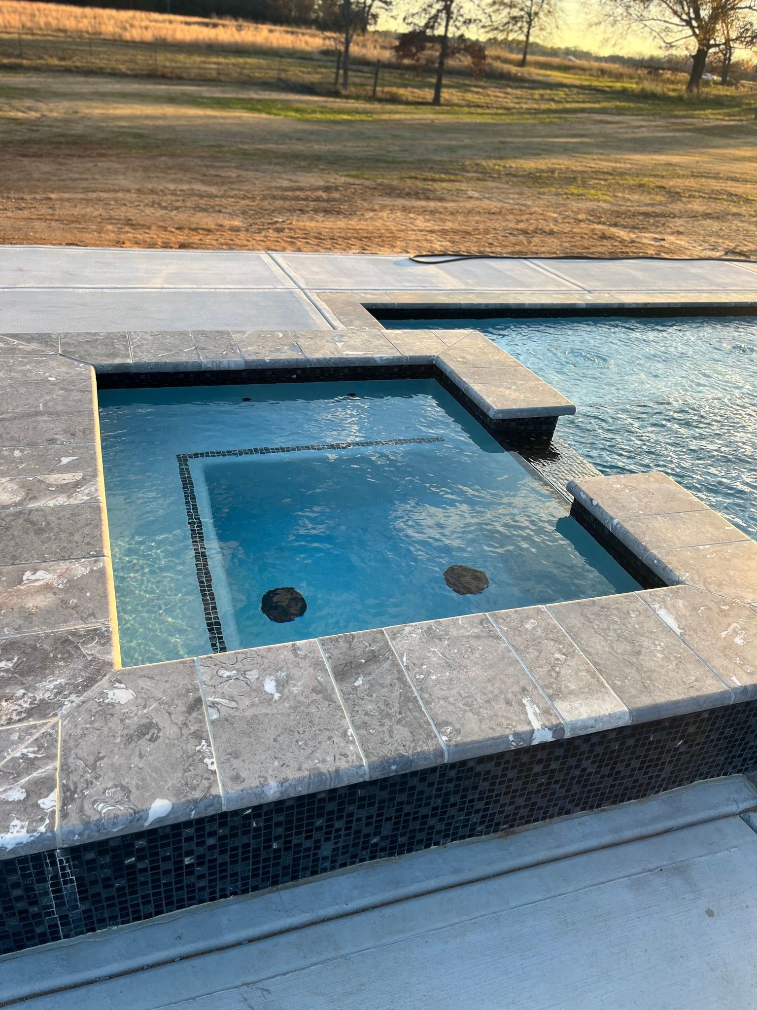 A swimming pool with a hot tub in the middle of it.