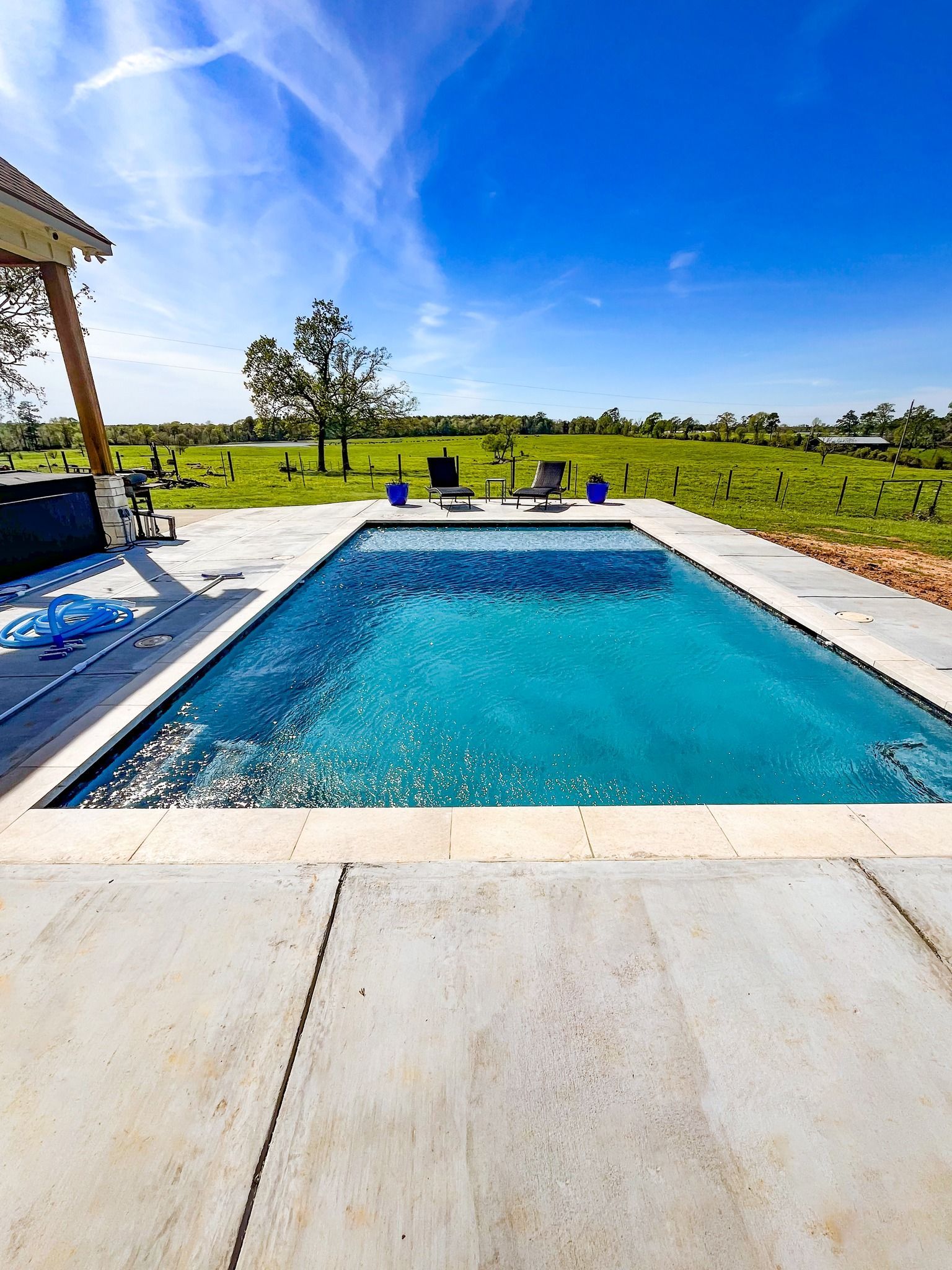 There is a large swimming pool in the middle of a field.