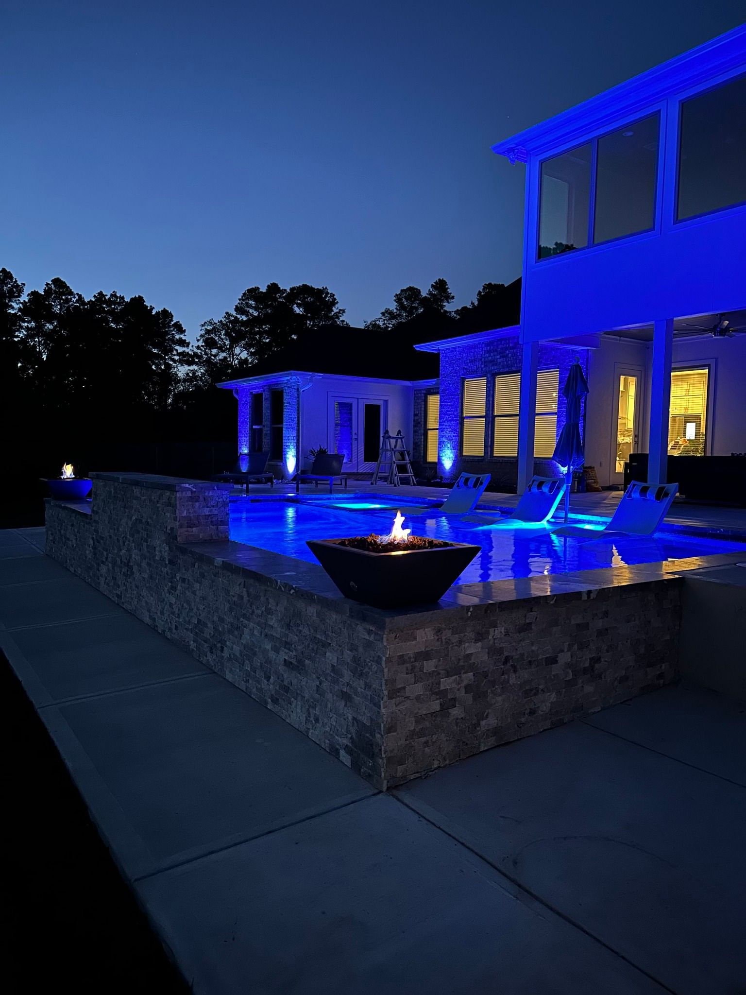 A large house with a swimming pool lit up with blue lights