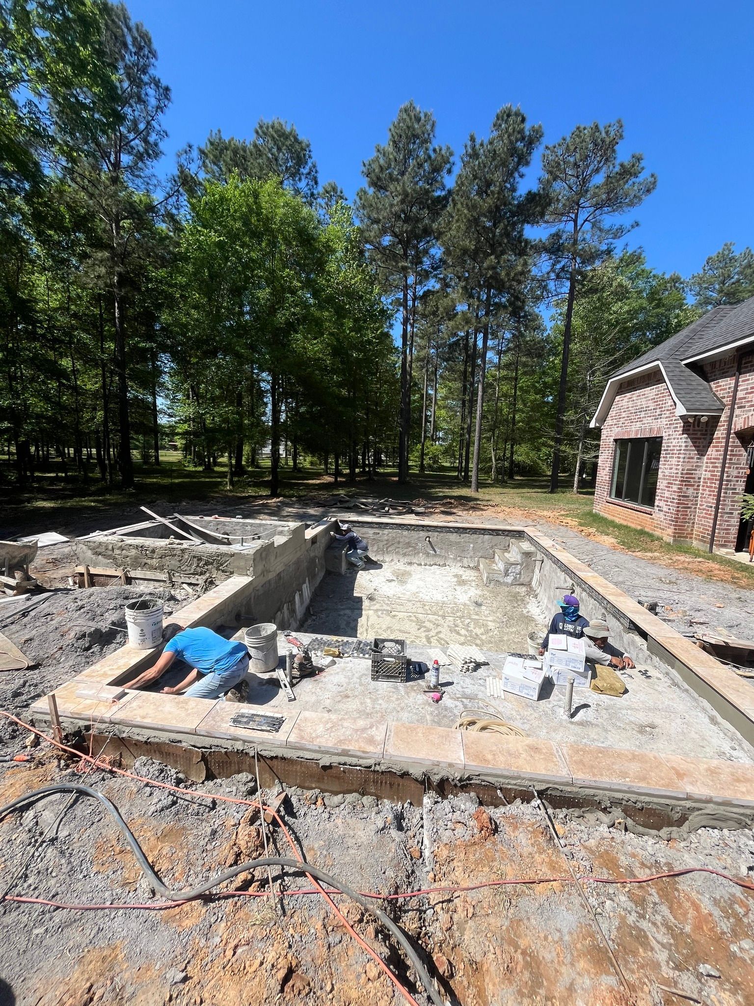 A man is laying on the ground next to a swimming pool under construction.