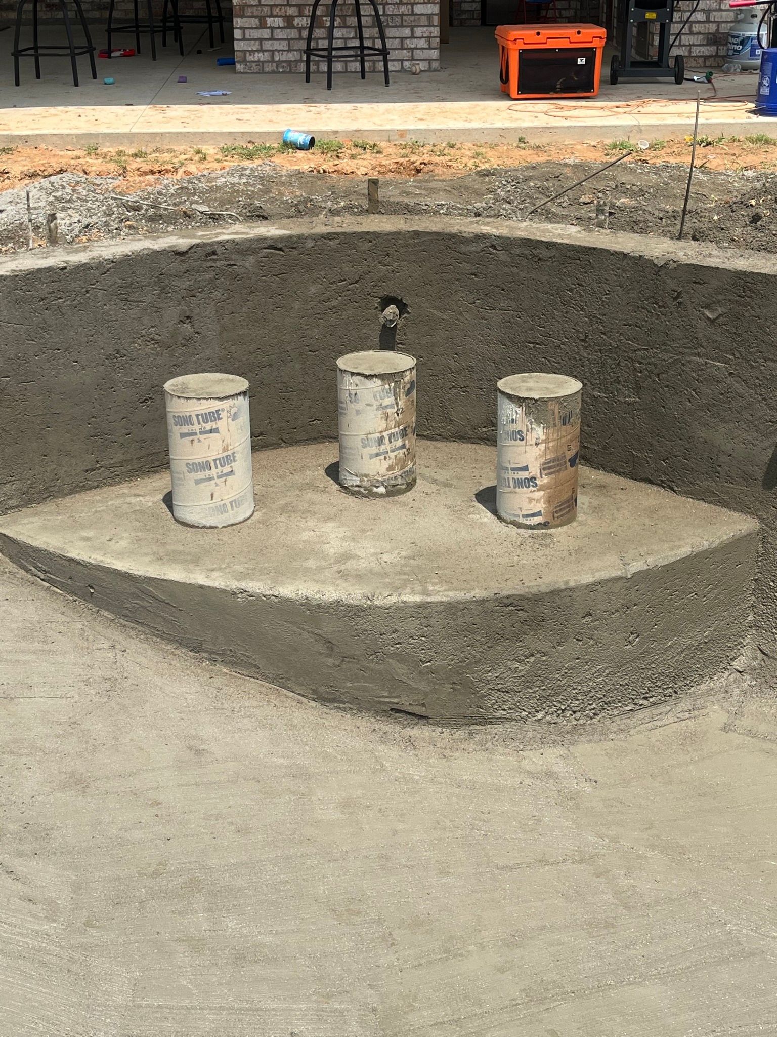 Three concrete cylinders are sitting in the middle of a concrete pool.