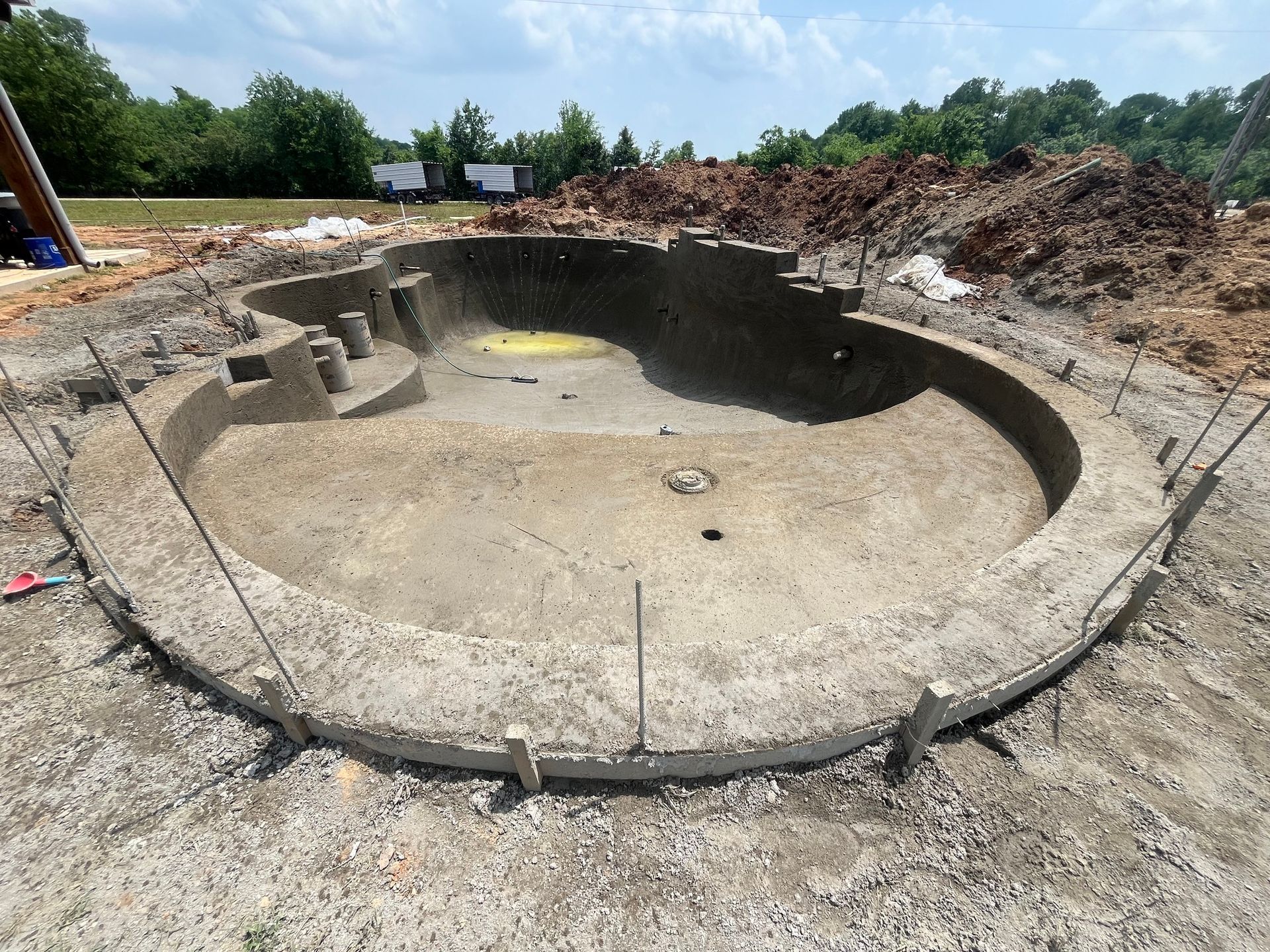 A large concrete pool is being built in a dirt field.