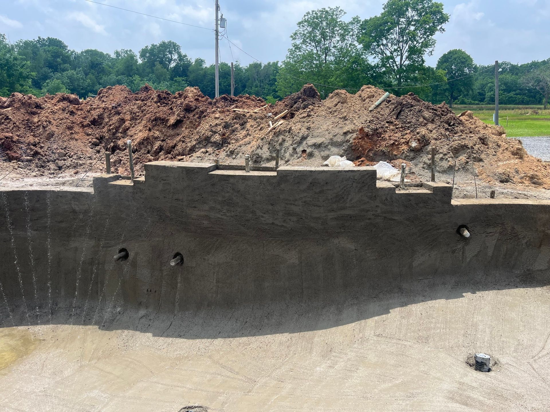 A large pile of dirt is sitting next to a concrete wall.