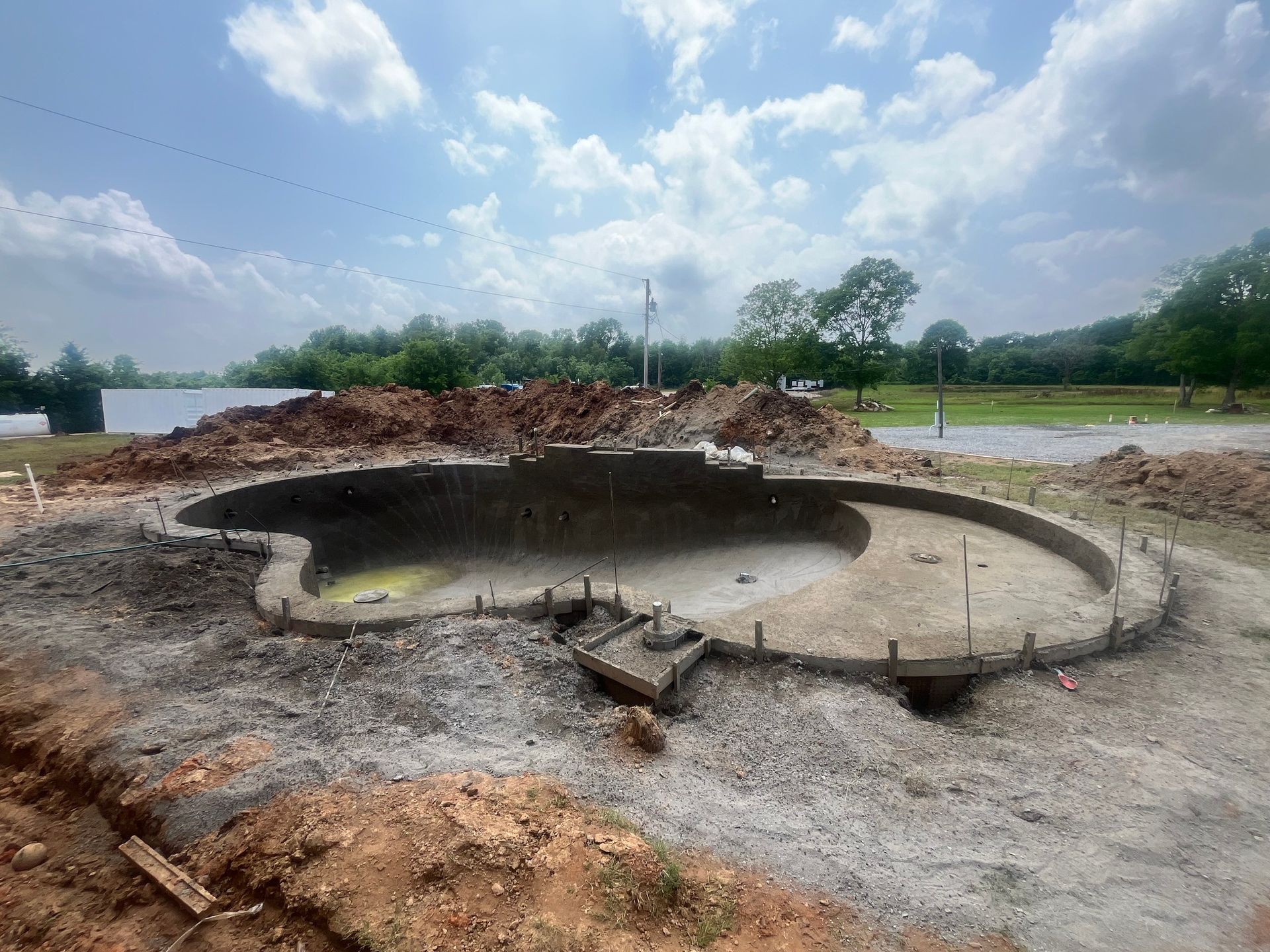 A large pool is being built in the middle of a dirt field.