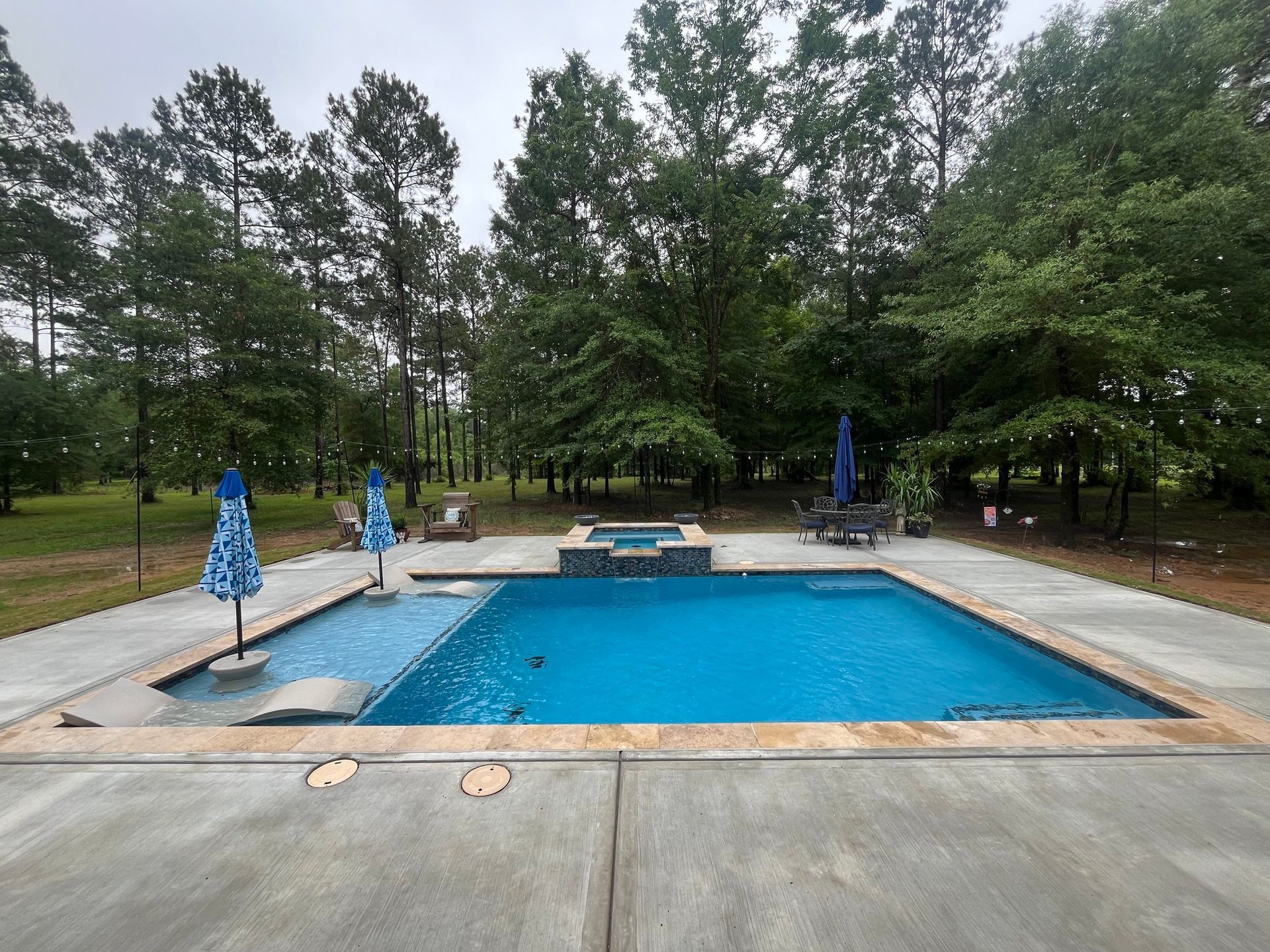 A large swimming pool surrounded by trees and umbrellas