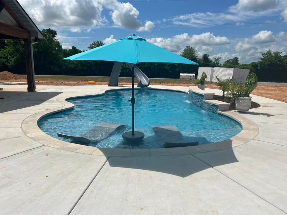 A large swimming pool with a blue umbrella in the middle