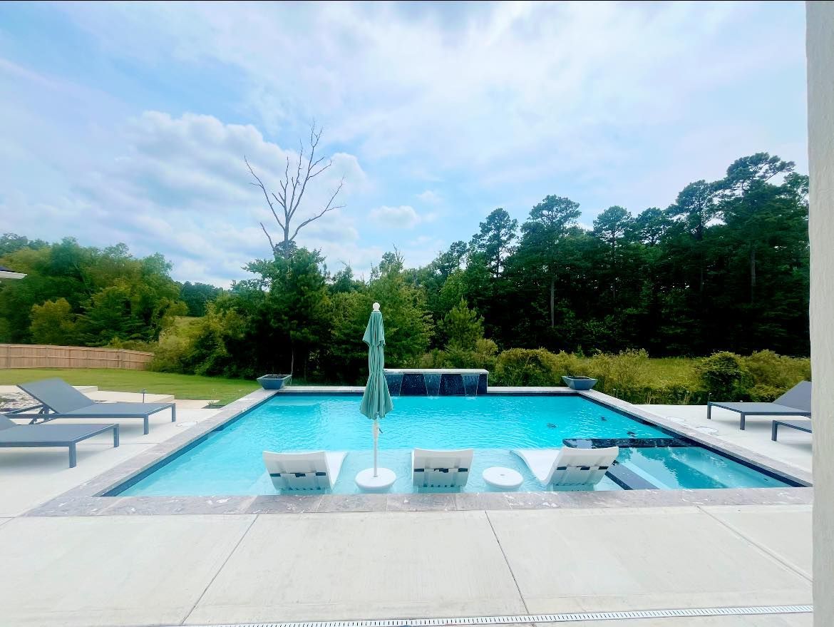 A large swimming pool surrounded by chairs and umbrellas on a sunny day.