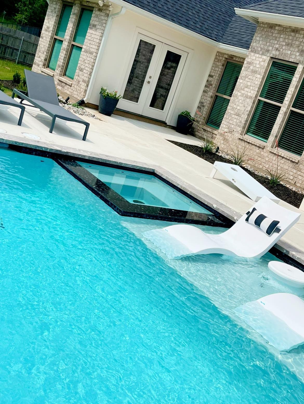 A large swimming pool with chairs in front of a house.