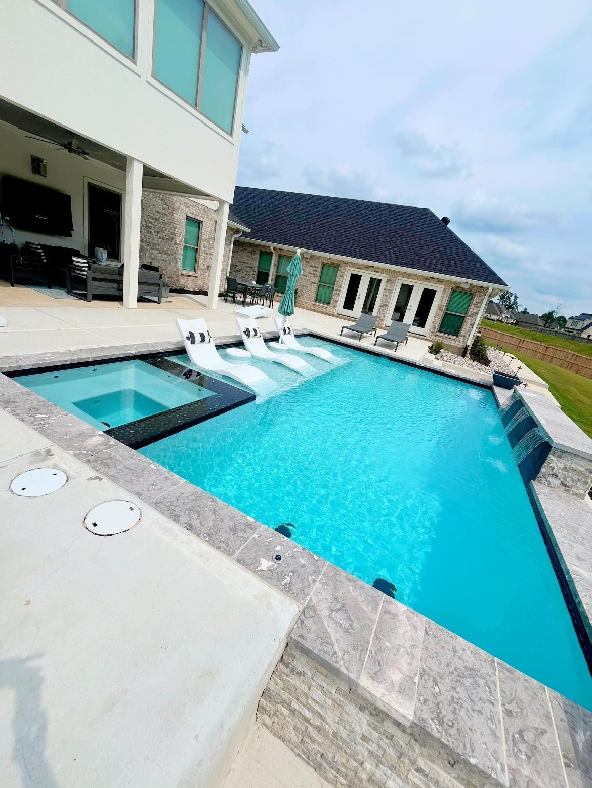 There is a large swimming pool in the backyard of a house.