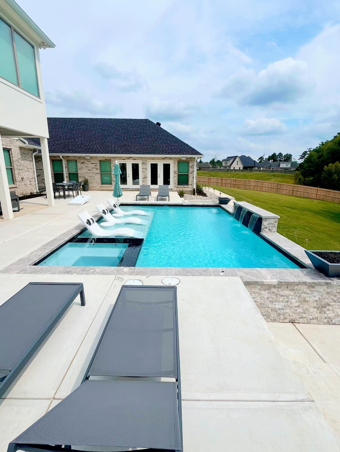 There is a large swimming pool in the backyard of a house.