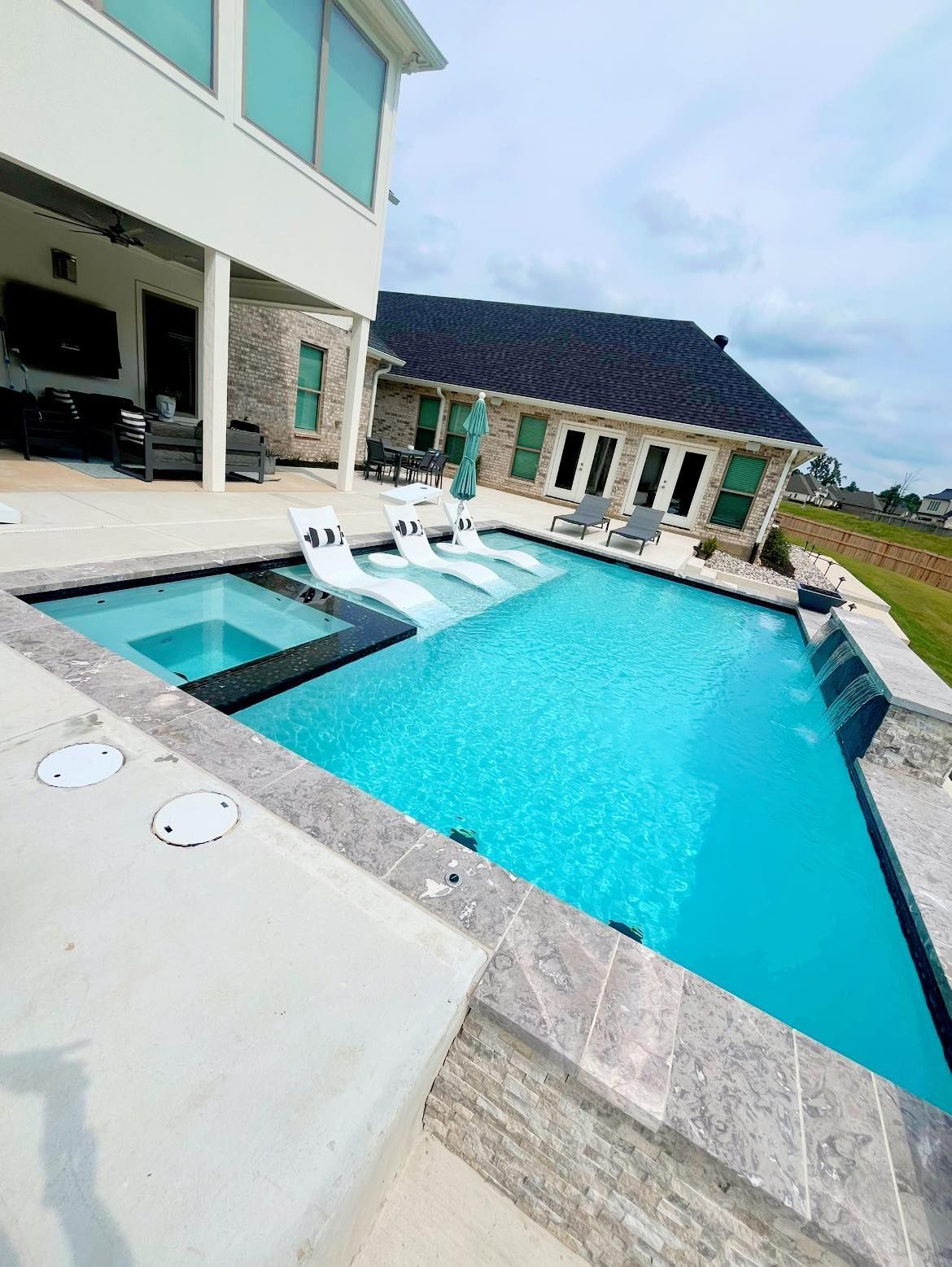 There is a large swimming pool in the backyard of a house.