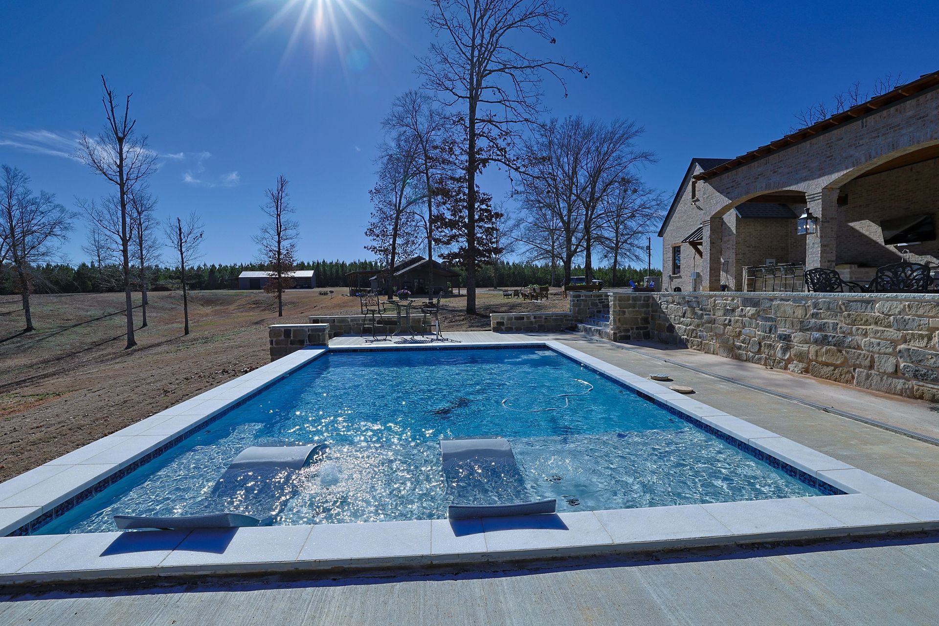 A large swimming pool with a house in the background