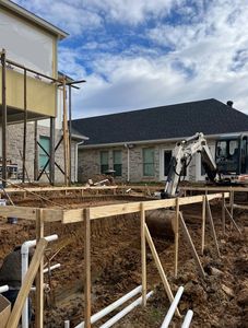 A construction site with a house in the background and a bulldozer in the foreground.