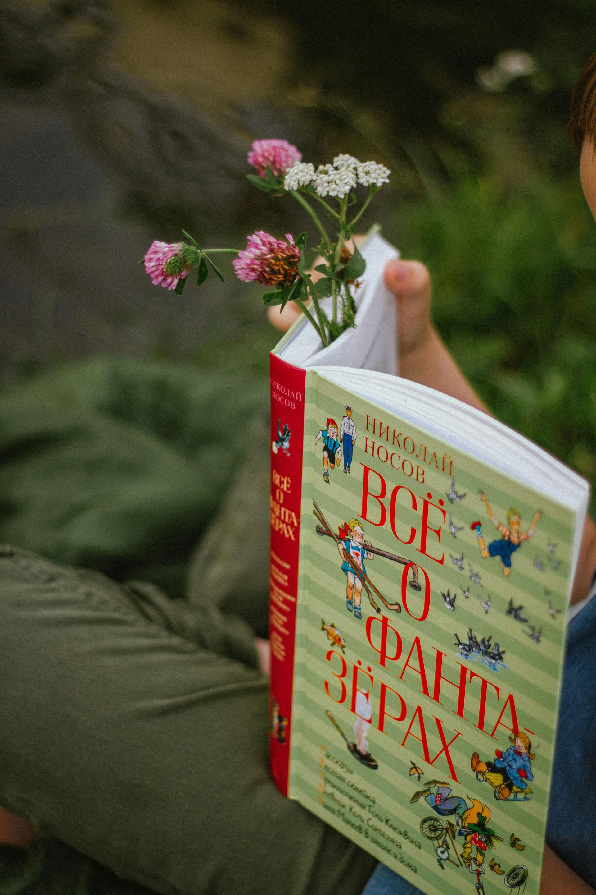 A person is holding a book with flowers in it.