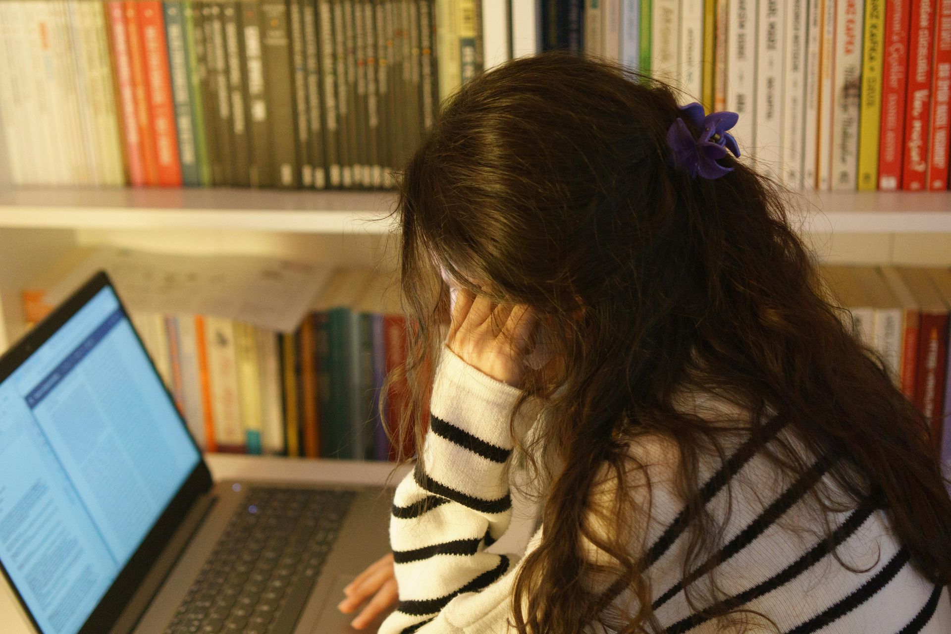 A girl is sitting in front of a laptop computer.