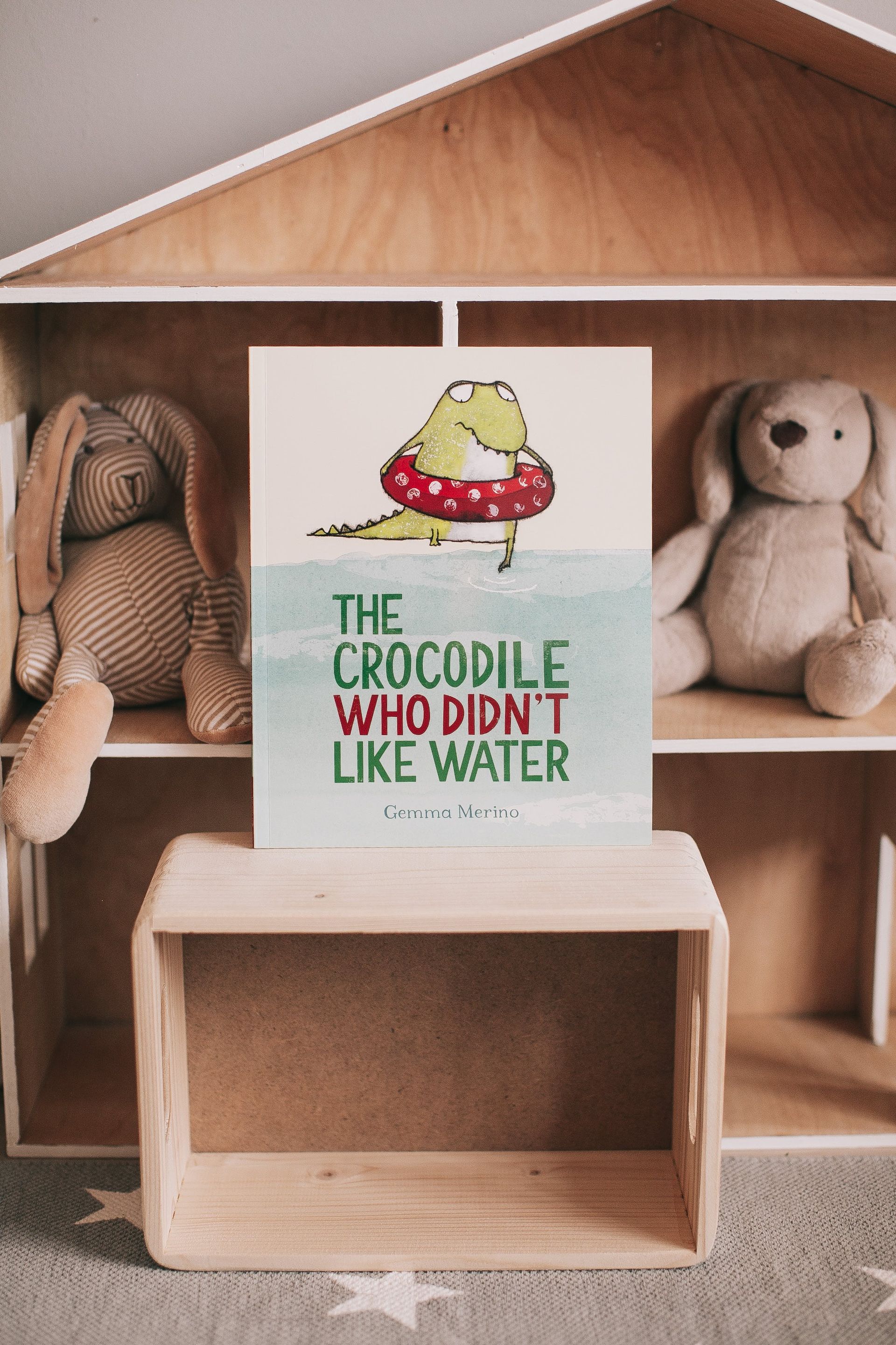 A poster of a crocodile wearing a swimming ring is sitting on a wooden box.