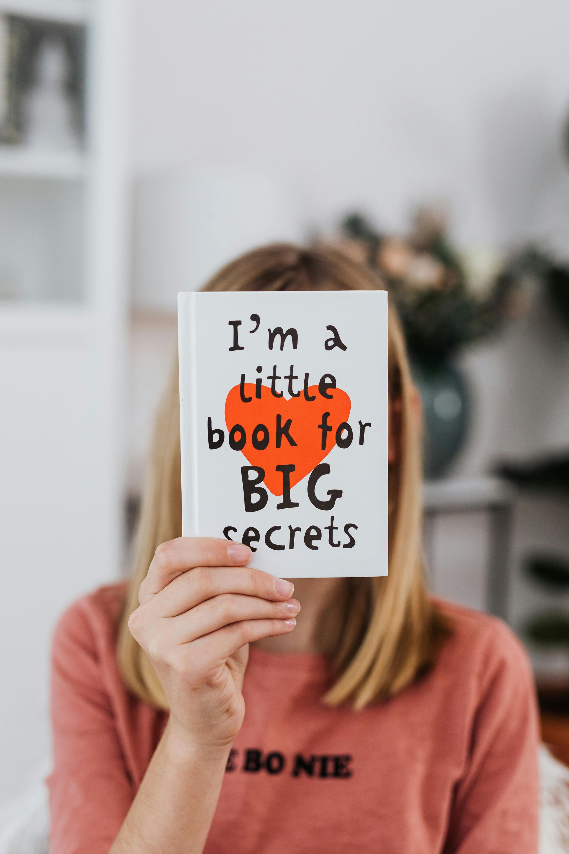 A woman is holding a book that says i 'm a little book for big secrets