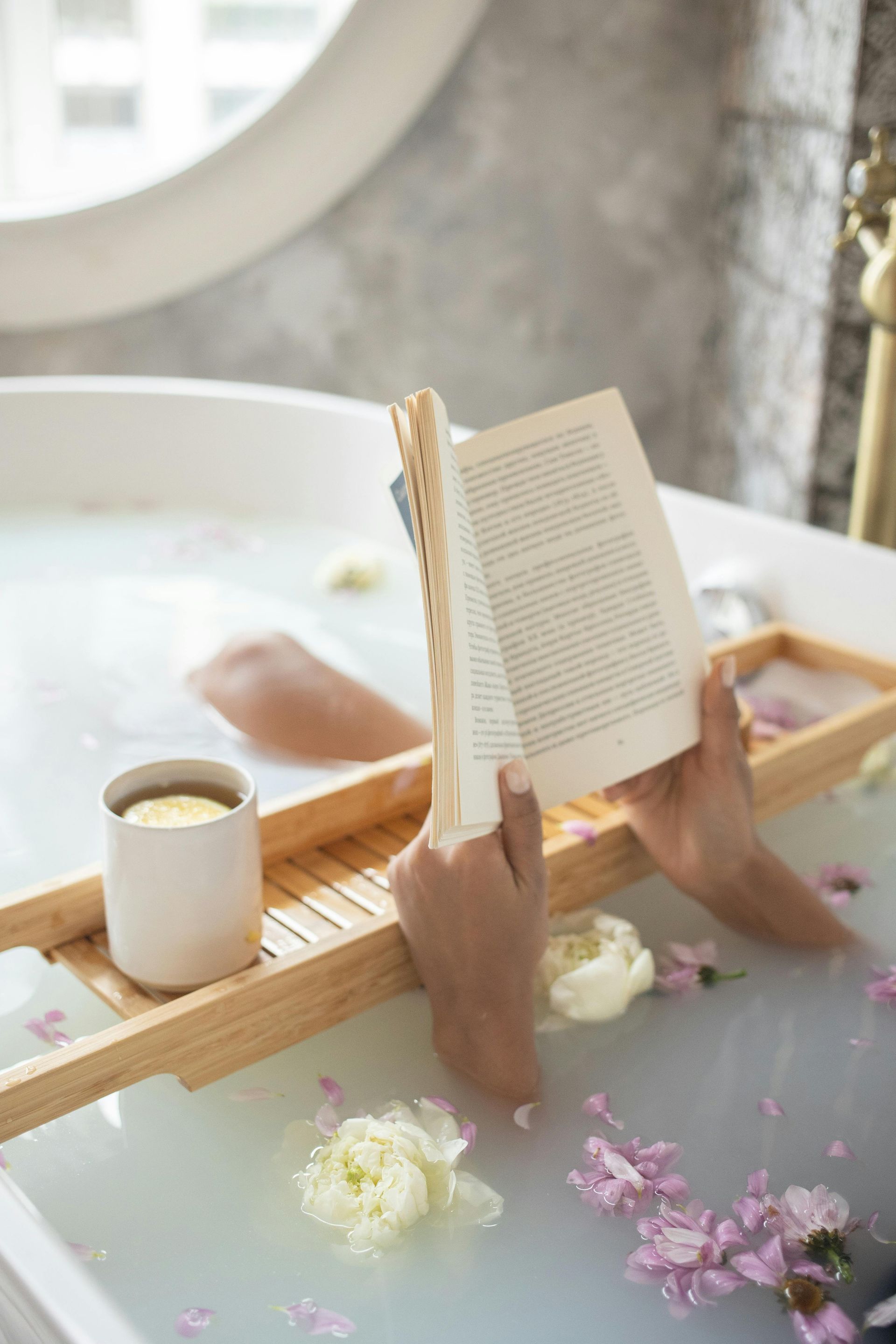 A person is taking a bath and reading a book.