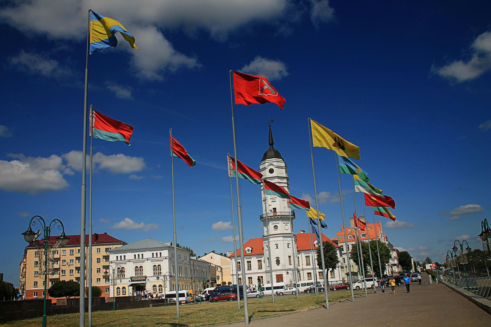 A bunch of flags are flying in the wind in front of a building