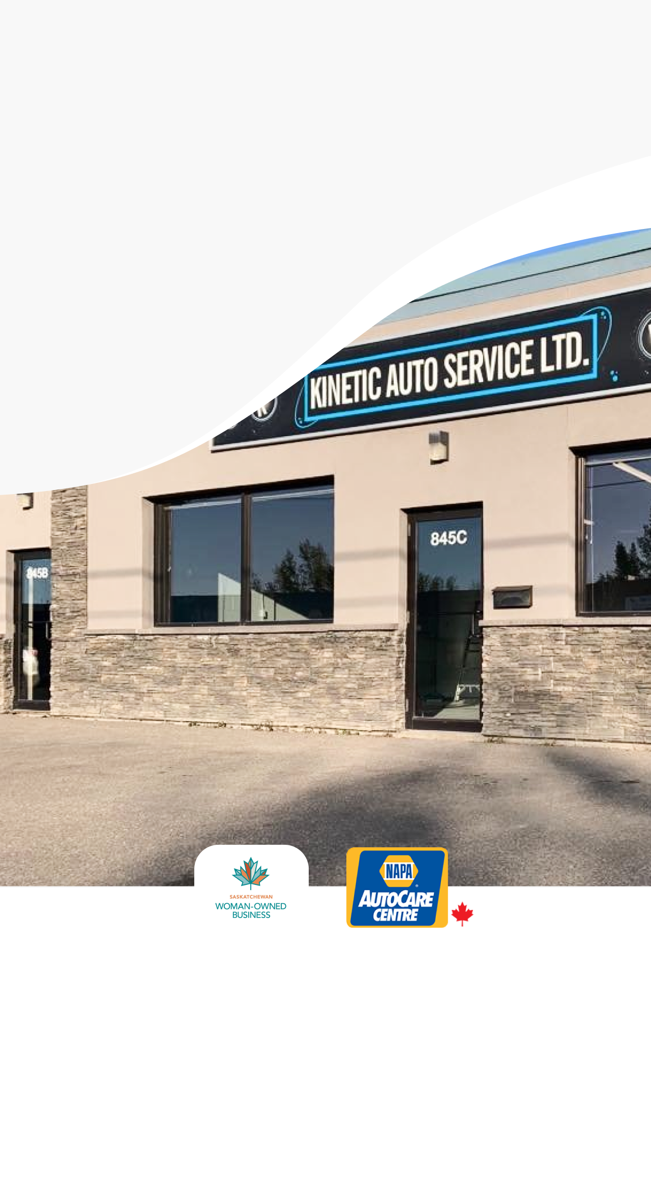 A blue car is parked in front of a building. | Kinetic Auto Service