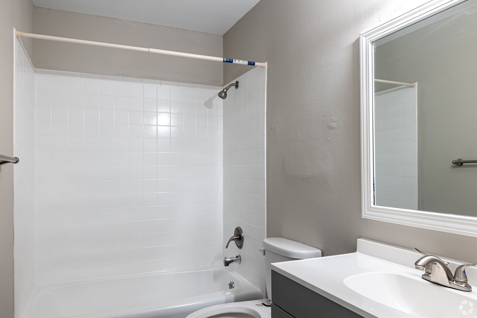A bathroom with a toilet , sink , shower and mirror.