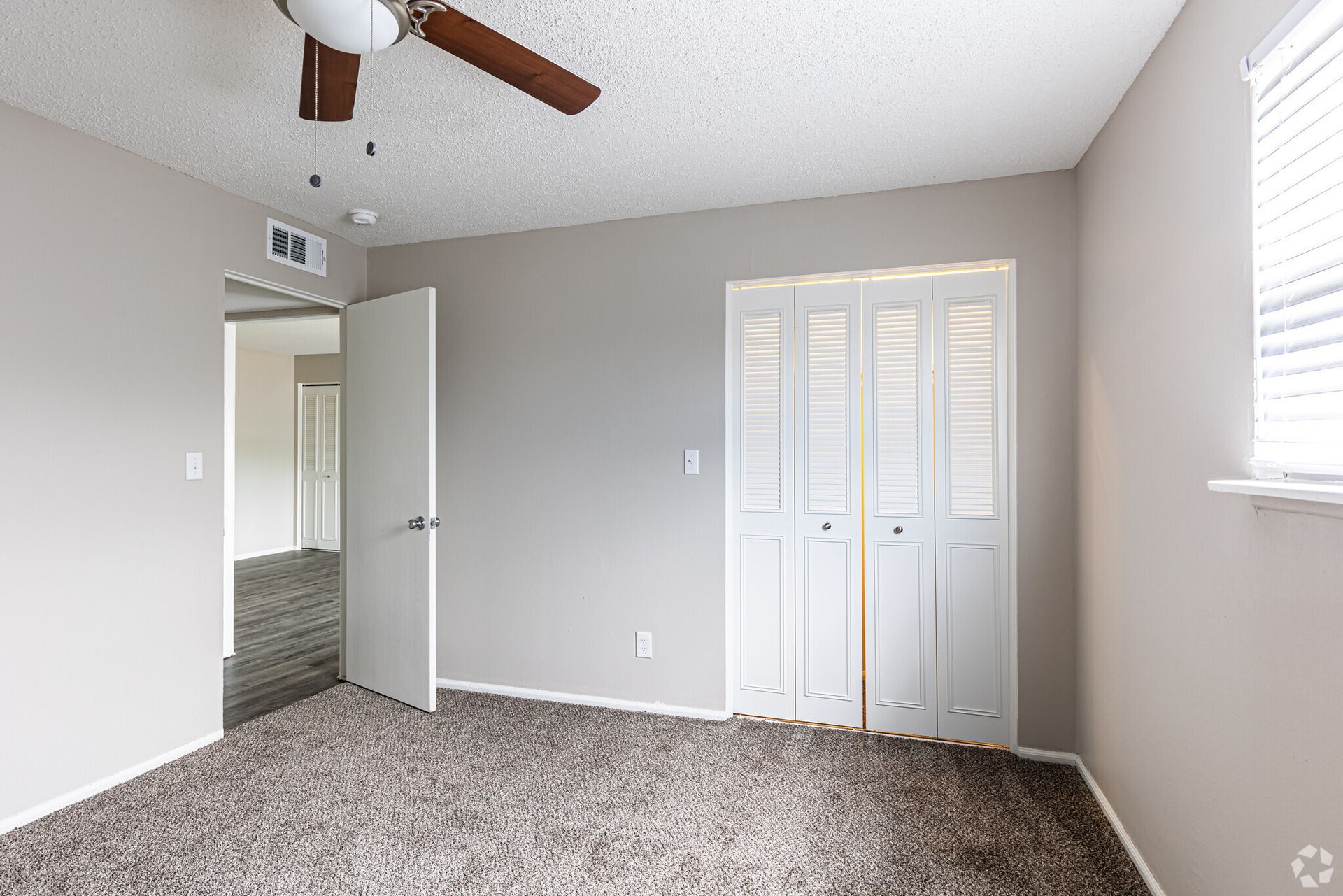 An empty bedroom with a ceiling fan and a closet.