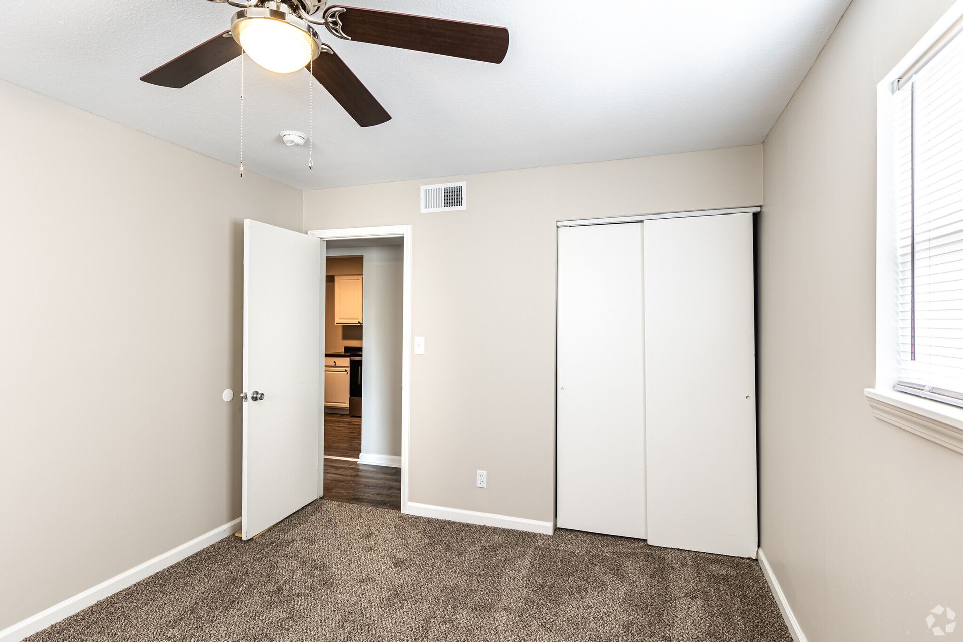 An empty bedroom with a ceiling fan and a window.