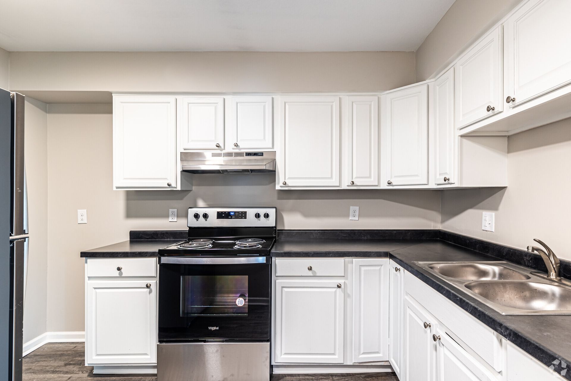 A kitchen with white cabinets , stainless steel appliances , and a sink.