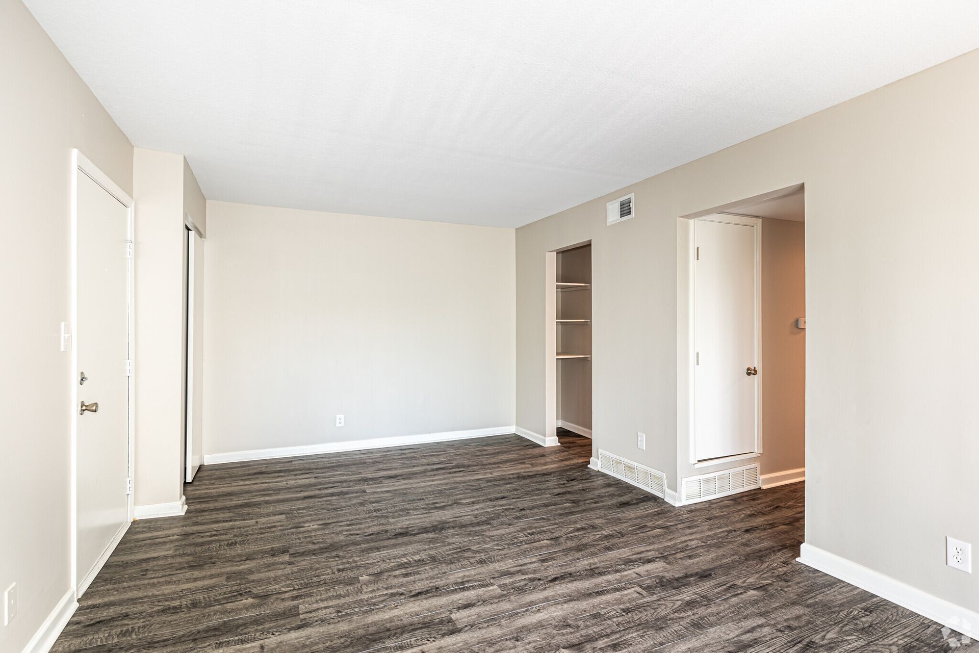 An empty living room with hardwood floors and a closet.
