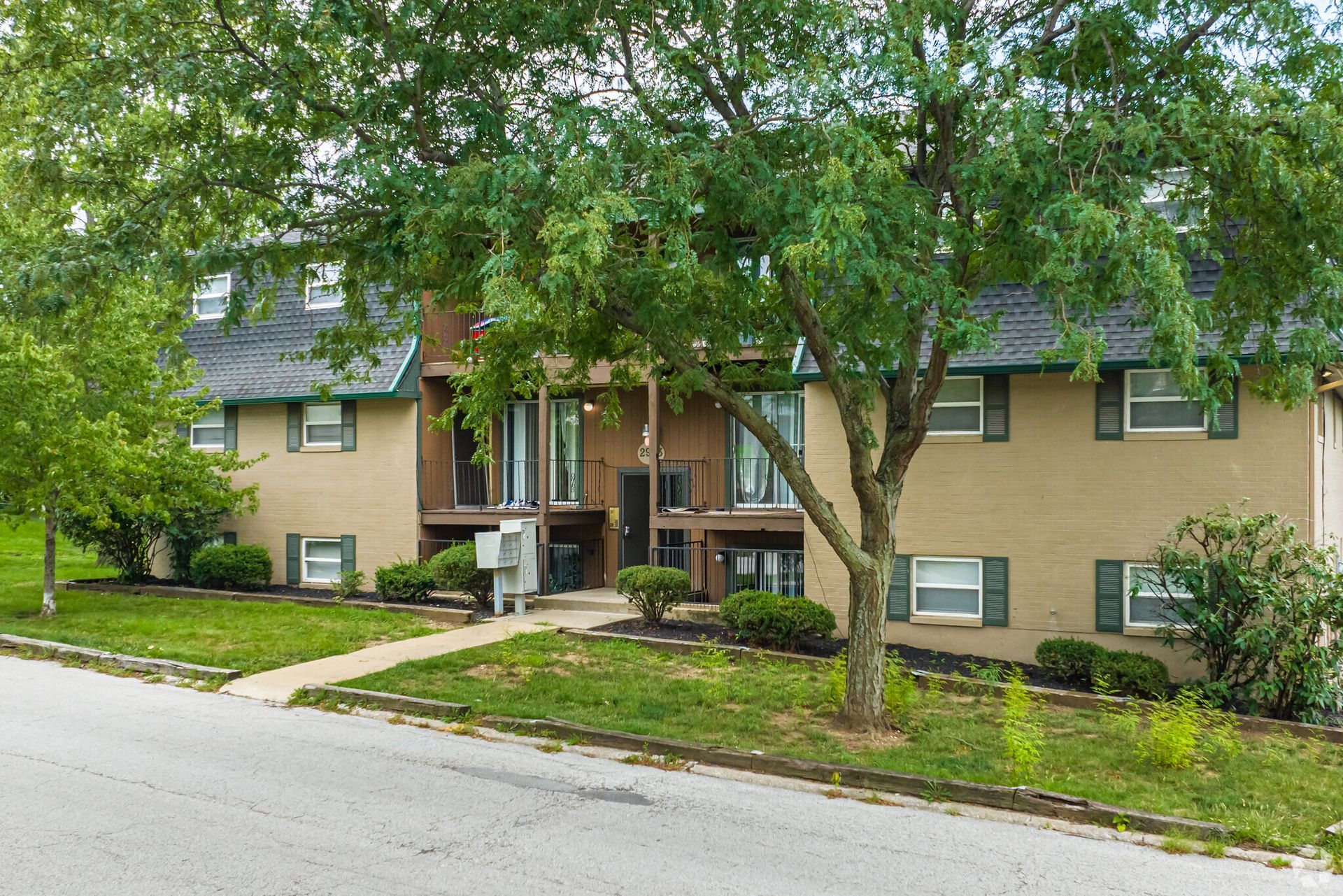 A large apartment building with a lot of windows and trees in front of it.
