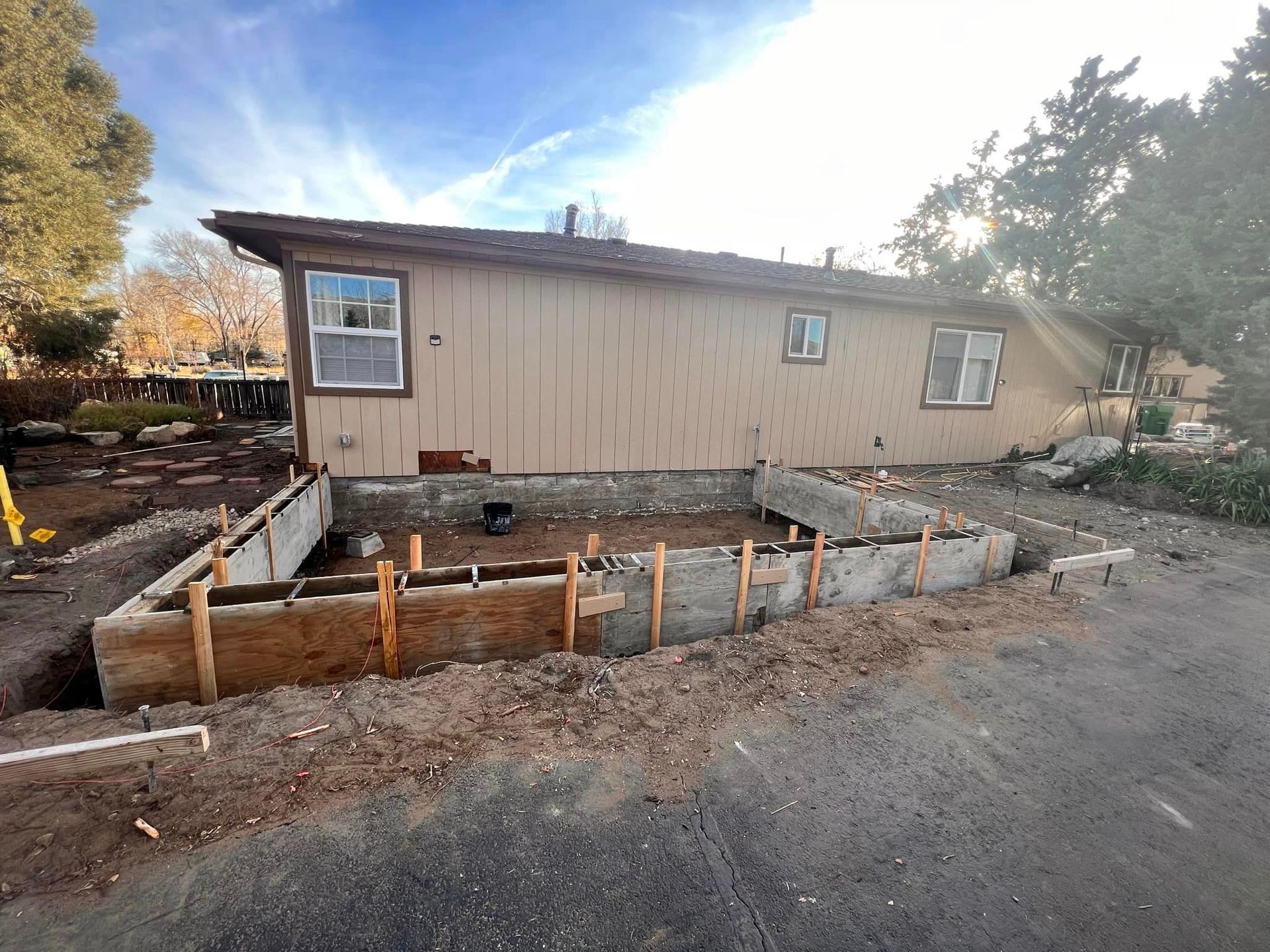 A house is being remodeled and a concrete foundation is being built in front of it.