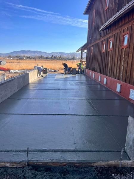 A concrete driveway is being built in front of a barn.