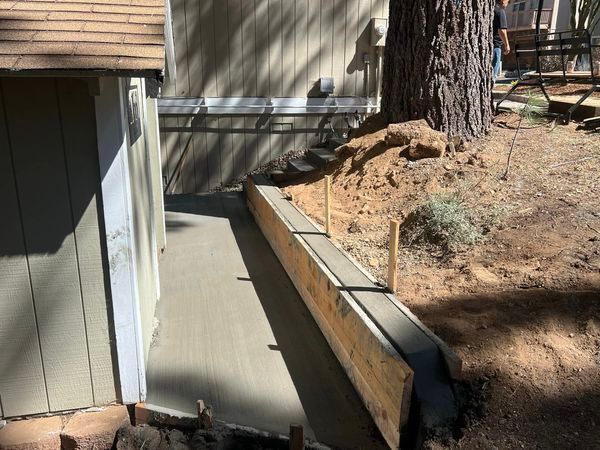 A concrete walkway is being built in front of a house.