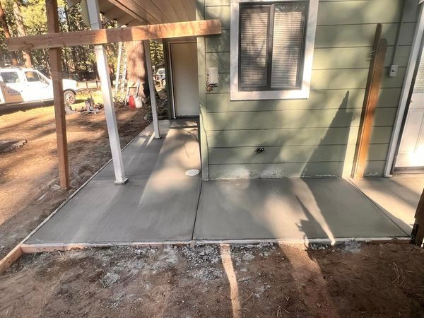 A green house with a concrete walkway in front of it