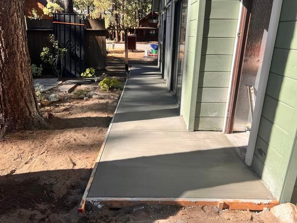 A concrete walkway is being built in front of a house