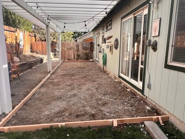A patio is being built in the backyard of a house.