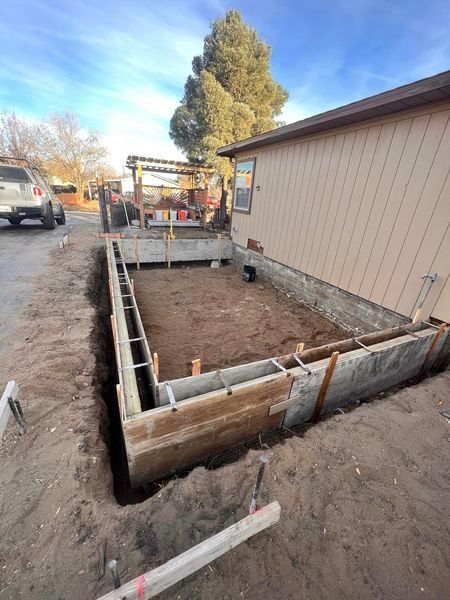A concrete foundation is being built in front of a house.